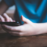 Boy sitting at table using a smartphone