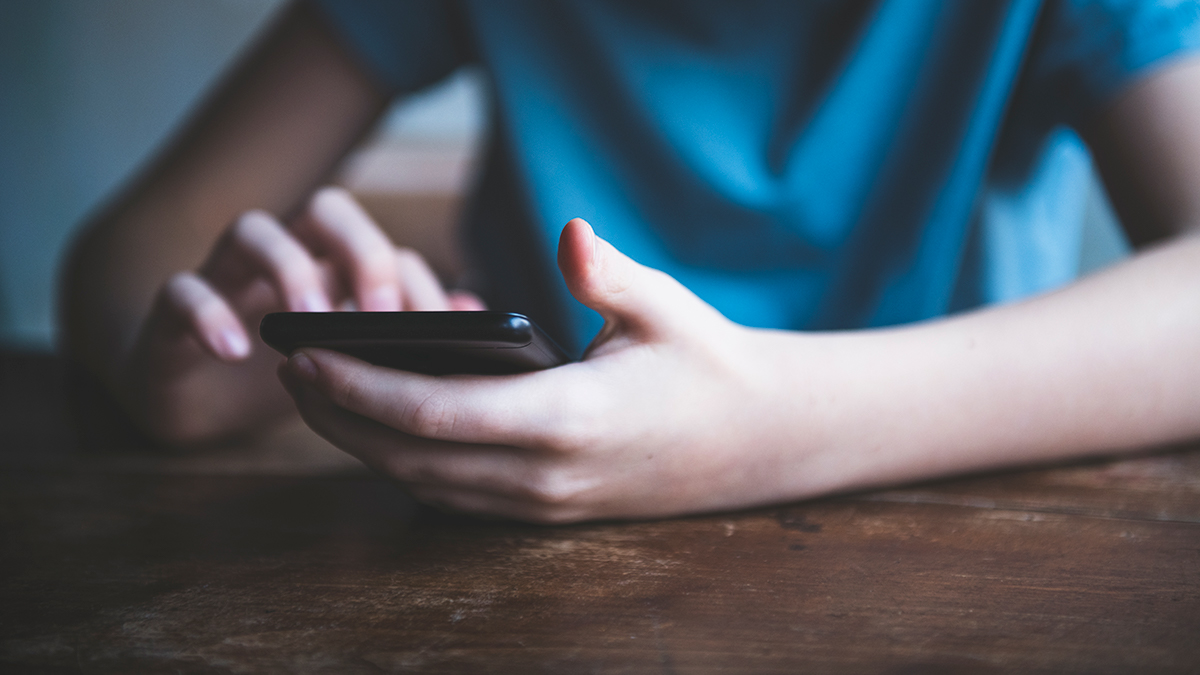 Boy sitting at table using a smartphone